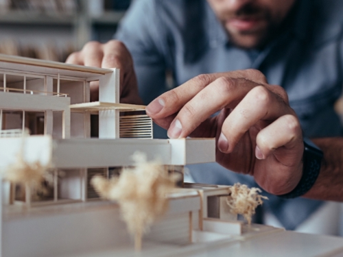 Zdjęcie architekta wykonującego model budynku z drewna.