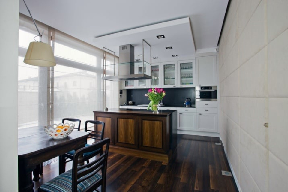 Eksluzywna biała kuchnia połączona z salonem, w kórym są meble stylizowane na stary styl
