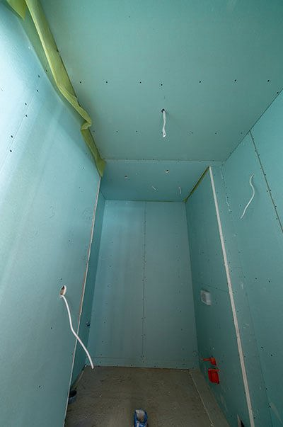 Łazienka opłytowana zielonymi płytami kartonowo-gipsowymi wodoodpornymi, odpornymi na działanie wody. Sufit podwieszany.