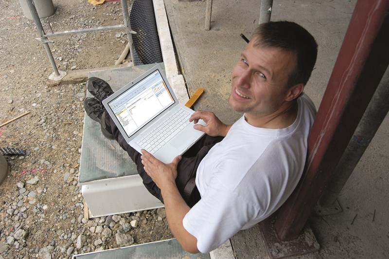Mężczyzna uśmiechnięty biały t-shirt, przy laptopie, pracujący nad projektem